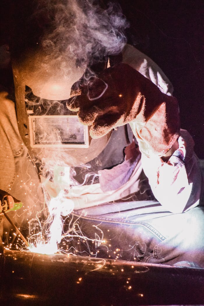 services-01 A welder in protective gear works with intense sparks during welding, showcasing skill and precision.