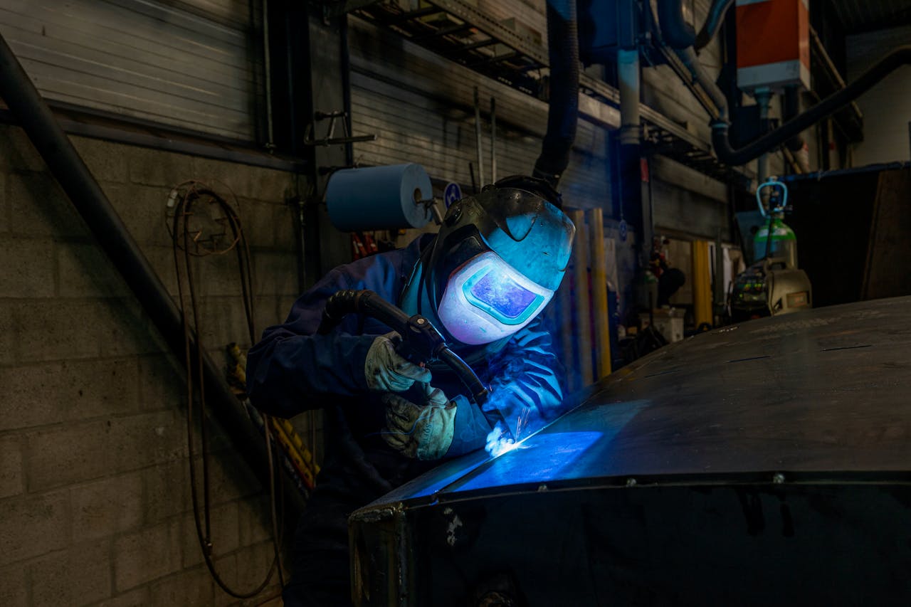 our-experience Welder wearing protective gear working in industrial workshop environment.