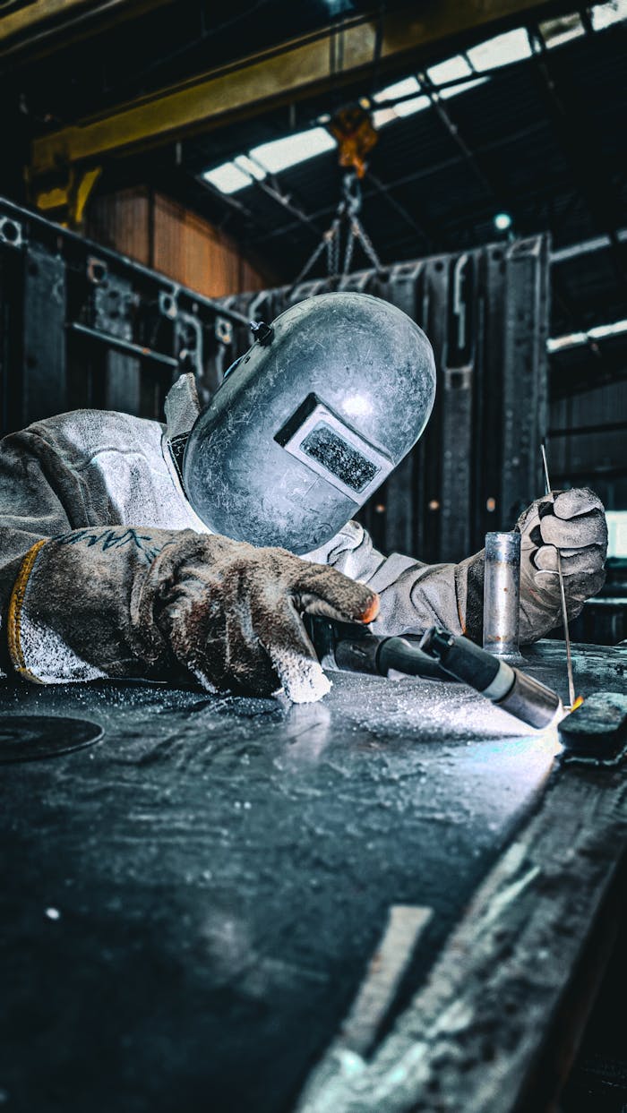 gallery-2 A skilled welder wearing protective gear performs welding in an industrial setting.